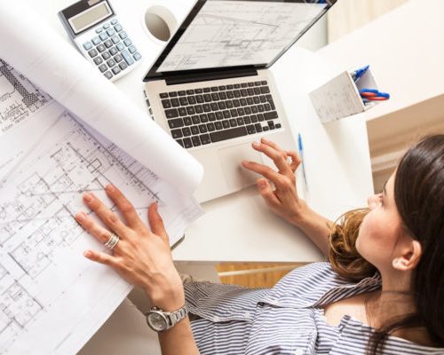 Female architect working at home.She looking at blueprint.